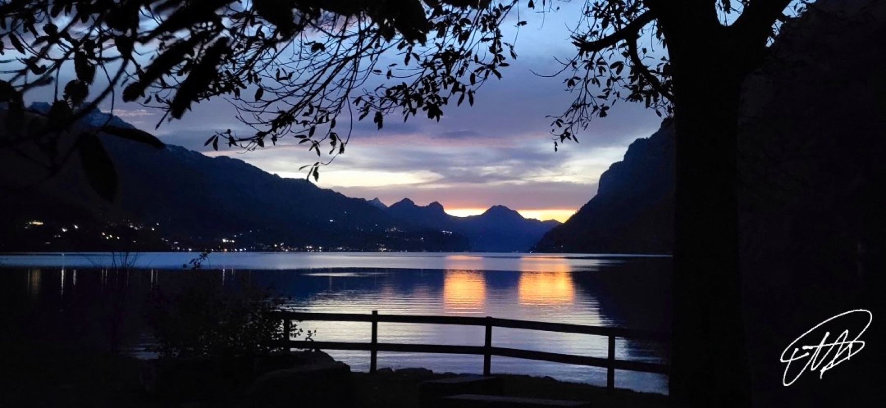 Abendstimmung über einem See zwischen dunklen Bergen