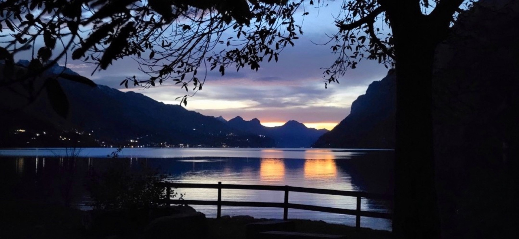 Abendstimmung über einem See zwischen dunklen Bergen